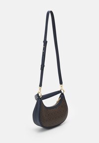 Granatowa torebka crossbody z złotymi akcesoriami, gładka skóra na górze i teksturowany brązowy wzorzysty materiał z przodu, o kształcie zakrzywionym.