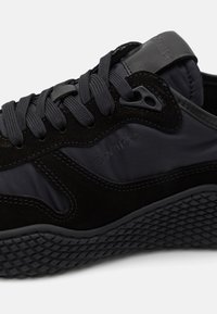 Černé tenisky vyrobené z kombinace semiše a syntetických materiálů, s texturovanou gumovou podrážkou a tónovým prošíváním. Viditelné logo Calvin Klein.