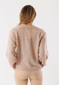 Maglione a maglia rosa chiaro con una vestibilità rilassata, colletto e polsini a coste, e una finitura testurizzata. Presenta un design semplice e una silhouette leggermente oversize.