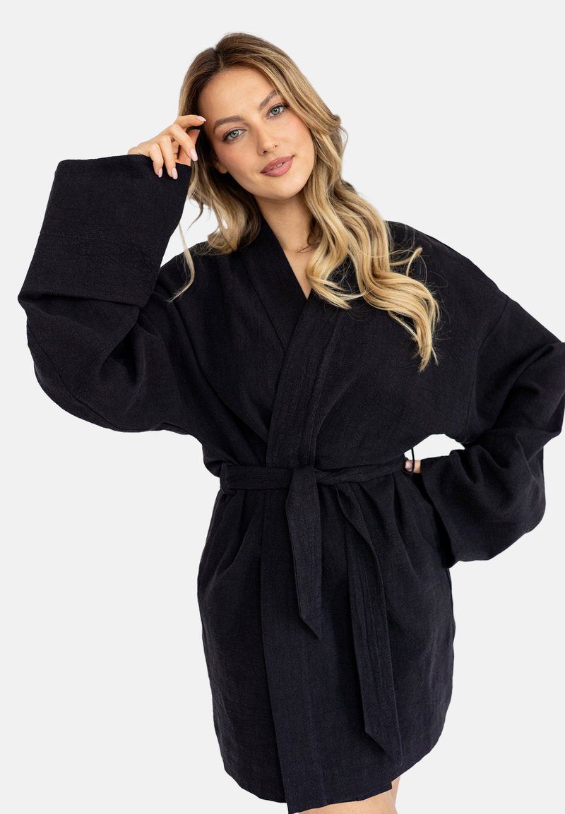 Czarna lniana szata z szerokimi rękawami, przewiązywana paskiem w talii, o luźnym kroju. Miękka tekstura z delikatnym połyskiem i czystymi liniami.