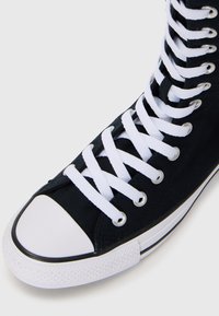 Mustad mustam võrkking, mis on valmistatud kangast, omad valged paelad, valge kummist varbakate ja must äär sokli ääres.