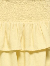 Žltá látka s nazberaným stehom na vrchu a nastrihaným, riaseným lemom dole.