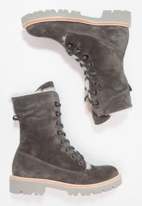 Stivali in suede grigi con lacci, dotati di una robusta suola in gomma grigia, fodera in pelliccia e un sottopiede in legno. Il design include occhialini metallici e una caviglia alta.