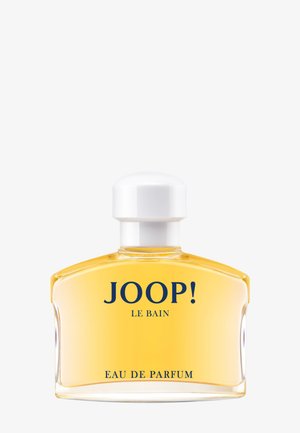 Läpinäkyvä lasinen parfyymipullo valkoisella korkilla, täytetty kullanvärisellä nesteellä, jossa on kyltti "JOOP! LE BAIN EAU DE PARFUM" tummansinisellä tekstillä.