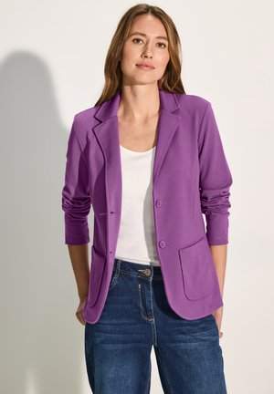 Lilla blazer med slidser, lange ærmer, to forlommer og knapper. Sammen med en hvid top og denim jeans.
