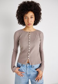 Bluză cu mânecă lungă și textură striată, în culoarea taupe, cu guler rotund și închidere cu nasturi pe față, cu nasturi de culoare deschisă. Asortată cu blugi cu talie înaltă.
