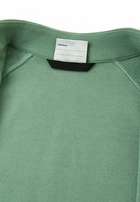 Felpa verde menta con una superficie liscia, dotata di un'etichetta interna con la scritta "Io ero qui." Dettaglio nero sul colletto.