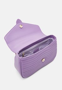 Borsa a tracolla in pelle trapuntata viola con chiusura magnetica. L'interno presenta una tasca con cerniera e una fodera liscia. Design compatto e strutturato.