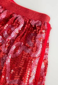Indumento in tessuto di paillettes rosse con superficie testurizzata, caratterizzato da una fascia in raso lucido e un motivo a vortice in tonalità rosa e rosse.