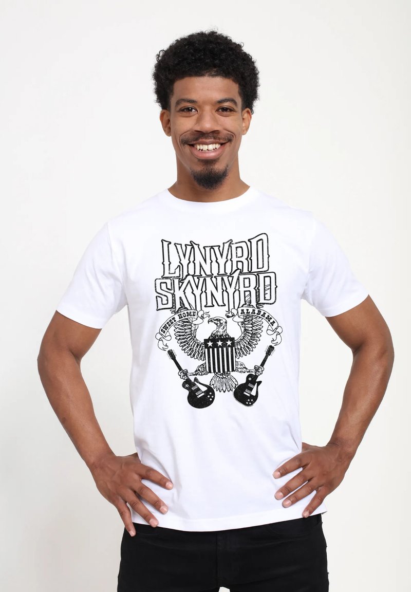 Bílý bavlněný tričko s černým grafickým designem "Lynyrd Skynyrd," orly, hvězdy a kytary. Krátké rukávy, kulatý výstřih.