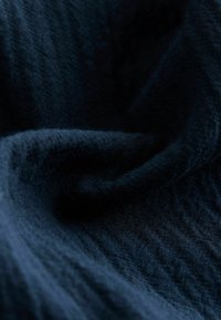 Sötét tengerészkék texturált szövet, lágy redőkkel és ráncokkal, enyhén matt felülettel, amely kiemeli a szövés mintáját és mélységét.