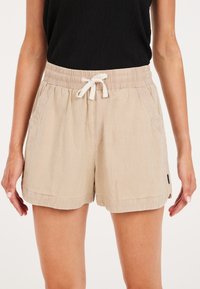 Beżowe lniane szorty z elastycznym pasem i sznurkiem, z bocznymi kieszeniami i lekko teksturowanym wykończeniem.