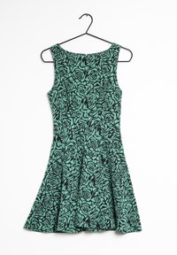 Robe verte avec un motif de roses noires fleuries, dotée d'une jupe évasée, présentée sur un cintre noir sur fond blanc.