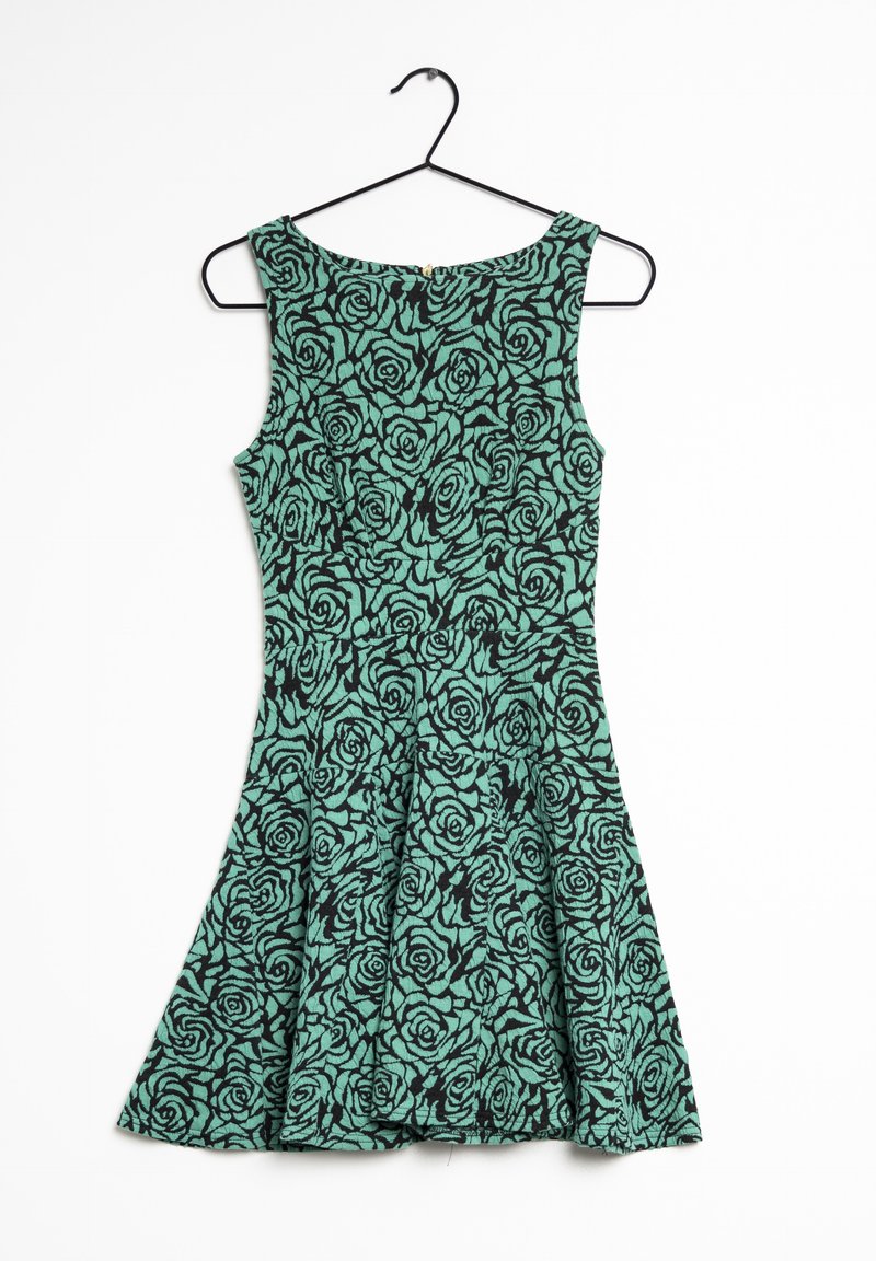 Robe verte avec un motif de roses noires fleuries, dotée d'une jupe évasée, présentée sur un cintre noir sur fond blanc.