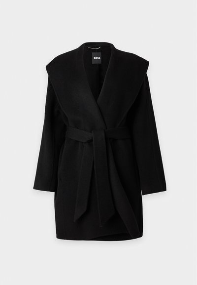 Manteau noir mi-long avec de larges revers et une ceinture en tissu nouée à la taille, présenté sur un fond uni gris clair.