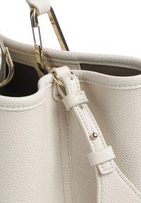 Borsa a mano in pelle bianca con superficie testurizzata, accessori in tono oro e tracolla con chiusura a fibbia. Primo piano dell'apertura.