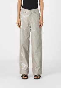 Γκρίζες, γυαλιστερές παντελόνες σε στυλ κροκοδείλου με φαρδιά πόδια, μπροστά τσέπες και κουμπί κλεισίματος, συνδυασμένες με μαύρες σανδάλια που έχουν χρυσές λεπτομέρειες.