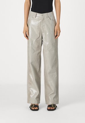 Pantalon large en simili-crocodile gris brillant avec poches avant et fermeture à bouton, associé à des sandales noires avec des accents dorés.