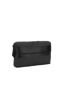 Borsetta nera con una superficie liscia e opaca. Dotata di chiusura con zip e una tracolla con marchio. Forma rettangolare, design compatto.