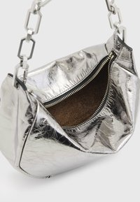 Sac à main métallique argenté avec une texture froissée, présentant une ouverture zippée et une anse en chaîne. Intérieur tapissé d'un matériau doux marron.