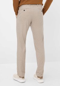 Beige skækbukser med flad front, sidelommer og baglommer med knap. Glat stof med en skræddersyet pasform.