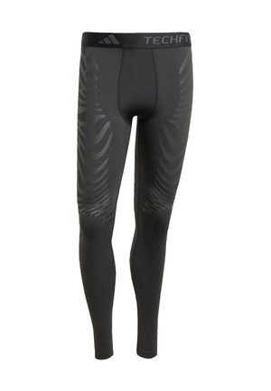 Leggings atléticos negros con una textura suave, que presentan un patrón de olas tonal en los laterales y una cinturilla con la marca "TECHFIT".