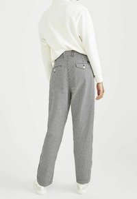 Pantaloni a vita alta a scacchi in bianco e nero con fit largo, dotati di tasche posteriori e design a gamba dritta.