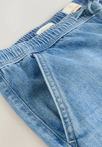 Șorturi din denim bleu deschis cu talie elastică, buzunare frontale și detalii de cusătură vizibile. Croială relaxată și textură moale.