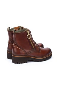 Botas de tobillo de cuero marrón con superficie texturizada, herrajes dorados, cremallera lateral y tachuelas decorativas. Suela de goma gruesa para tracción.