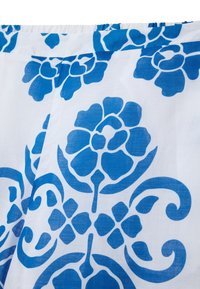 Tissu floral abstrait présentant de grandes fleurs bleues et des motifs tourbillonnants sur un fond blanc, fait en coton léger ou un matériau similaire.