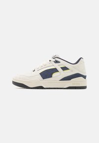 Sneakers con una toma in suede crema, accenti in blu navy e dettagli gialli. Presentano una suola in gomma nera e tessuti testurizzati per una maggiore aderenza.