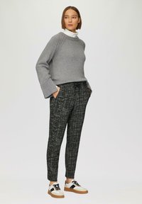 Grijze gebreide trui met geribbelde boorden, zwart-wit gestreepte broek en witte sneakers met zwarte accenten. Eenvoudig, modern ontwerp.
