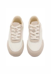 Baskets blanches avec des accents en suède beige clair, bout rond, profil bas et lacets plats. Texture lisse avec des détails de panneaux en contraste.
