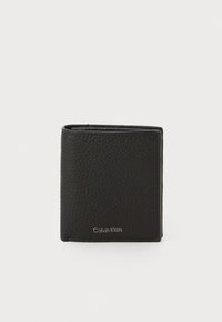 Cartera de cuero negra con acabado texturizado, diseño bifold y detalle en relieve "Calvin Klein" en la parte inferior frontal. Forma compacta y elegante.