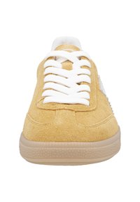 Baskets en daim jaune moutarde avec lacets blancs, bout rond, surface texturée et semelle extérieure en gomme flexible. Design épuré avec des accents minimalistes.