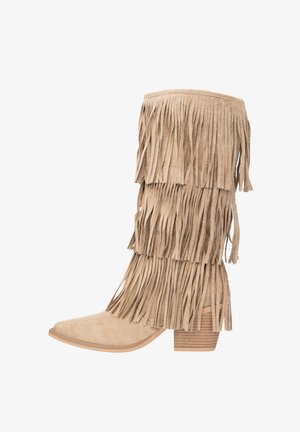 Botte en daim beige avec un détail à franges superposées, un bout pointu et un talon empilé. La texture est douce, et le design est haut et ajusté.
