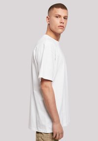 White cotton t-shirt featuring short sleeves and a relaxed fit, with a round neckline and smooth texture. Side view displayed.
