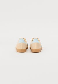 Lysblå og beige sneakers med tekstureret meshdesign, gummisål og accenter. Low-top stil med buet bagside.