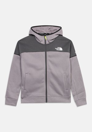 Veste à capuche zippée en gris clair avec le haut de la poitrine et les épaules en gris foncé, arborant le logo The North Face sur la poitrine et la manche.