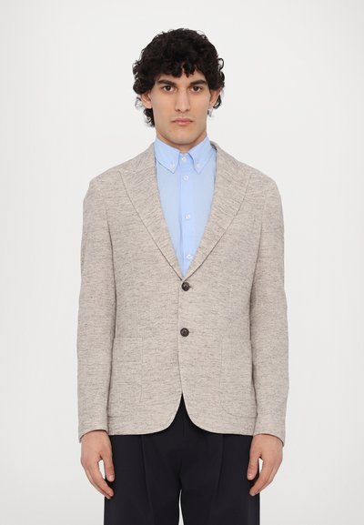 Hell gefärbter, strukturierter Blazer mit einer Einzelknopfverschluss, zwei vorderen Taschen und aufgesetzten Revers, getragen über einem hellblauen Hemd.