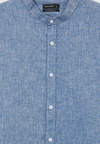 Camicia azzurro chiaro, con bottoni, realizzata in lino, caratterizzata da colletto a stand, tessuto testurizzato e bottoni bianchi lungo la pattina.