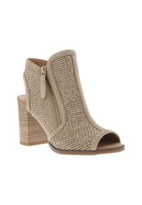 Bottines en tricot beige à bout ouvert, avec fermeture éclair sur le côté et clous décoratifs. Elles présentent un talon carré et un design tissé texturé.