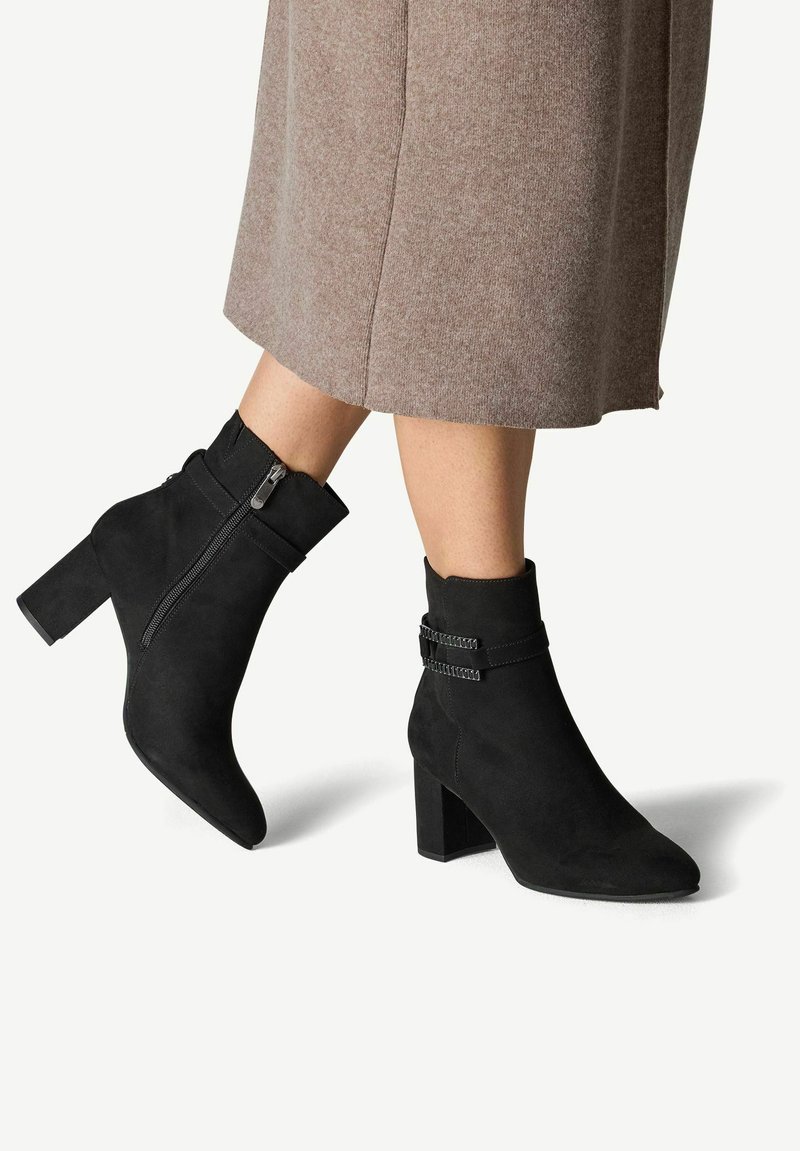 Botine negre din suede, cu toc pătrat, fermoar lateral și accente cu catarame duble în partea superioară. Textură netedă și design cu vârf ascuțit.