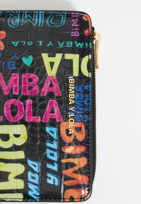 Czarny portfel w wzór krokodylej skóry z kolorowym tekstem i logo w neonowych odcieniach. Posiada złoty zamek i branding 'BIMBA Y LOLA'.
