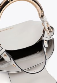 Svetlošedá kabelka so zlatou rukoväťou, otvorená na zobrazenie tmavého interiéru. Obsahuje popruh a zlaté kovové doplnky.