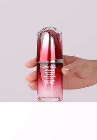 Shiseido Ultimune Power Infusing Concentrate in een gradiënt rood en doorzichtig flesje, met een gladde, gebogen vorm en zilveren accenten.
