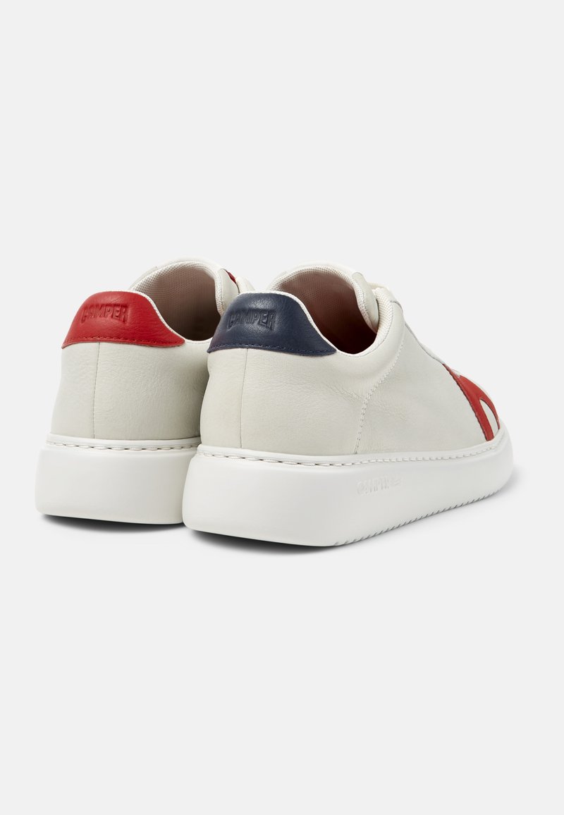 Pair of low-top white leather sneakers with thick white soles, red and navy heel tabs, and red accents on the sides, shown from the back.