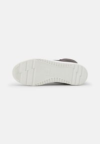 Shoe sole with a white rubber base, textured for grip, featuring a flat design and horizontal grooves. Dark upper material not visible.