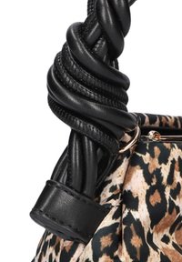Black leather bag handle twisted into a knot, attached to a patterned fabric with beige and black leopard print. Gold hardware visible.