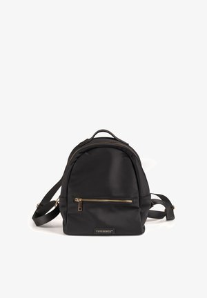 Mochila de nylon negra con un diseño redondeado, adornos de hardware dorado, un bolsillo delantero con cremallera y correas ajustables. Logo exhibido en el frente.